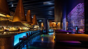 A modern bar area with a long counter, multiple bar stools, and ambient lighting. - Walt Disney World Swan (Lake Buena Vista)
