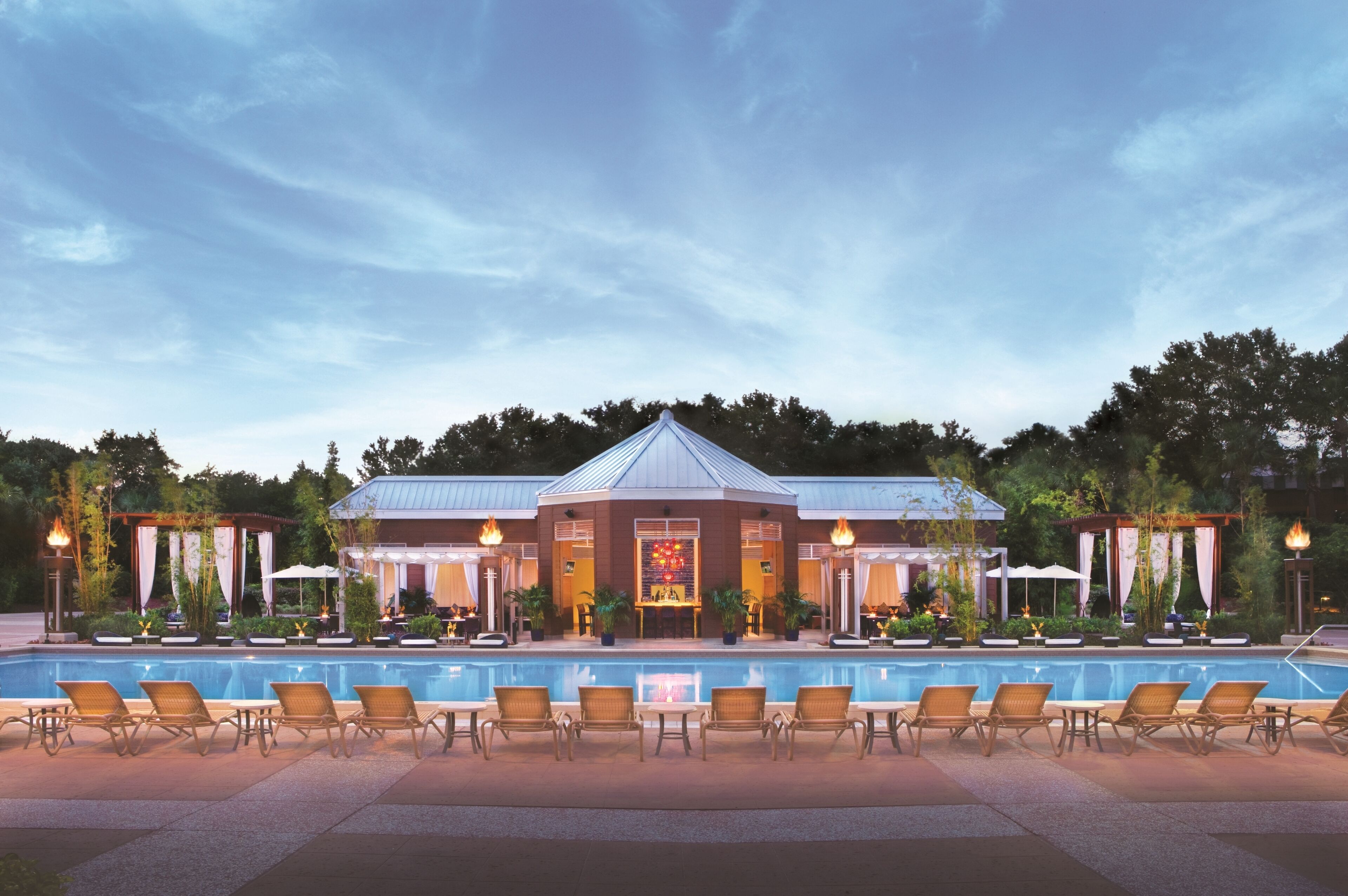 A hotel with a swimming pool, outdoor seating, and a covered area with a fire feature.
