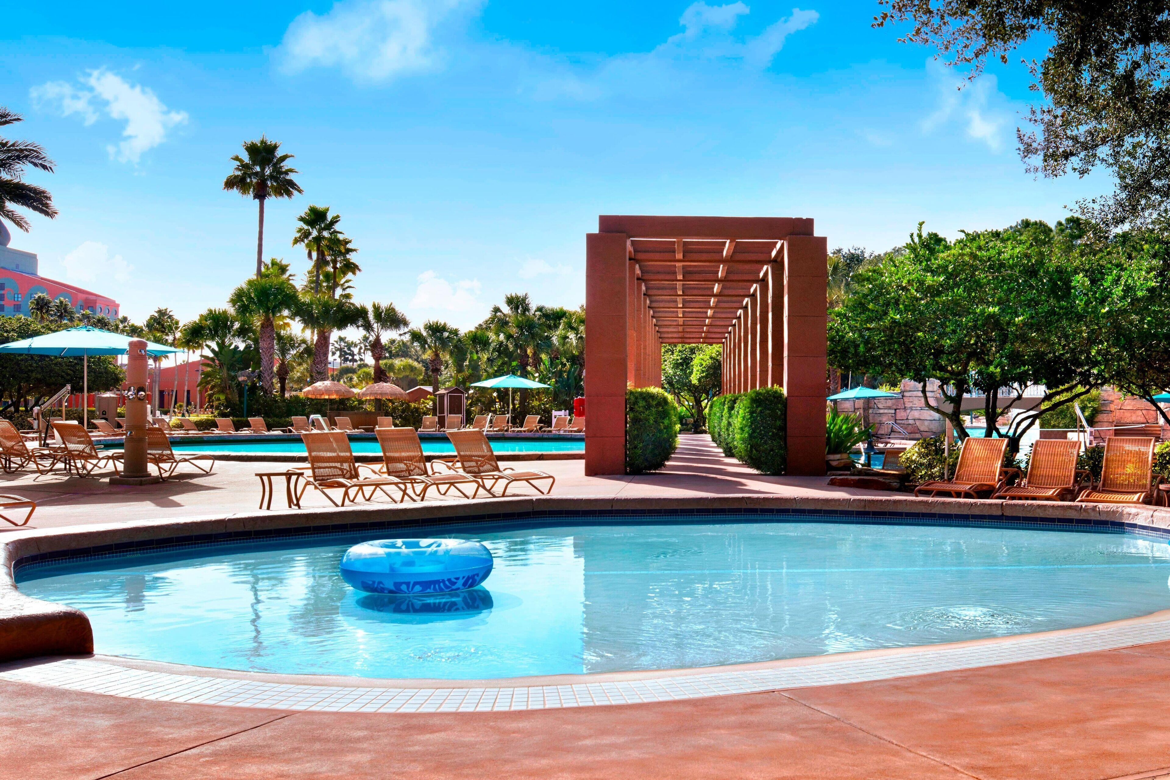 A pool area with lounge chairs, a blue inflatable float, and a pergola structure.