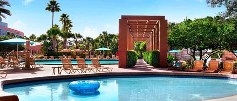 A pool area with lounge chairs, a blue inflatable float, and a pergola structure.