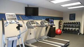 Un gimnasio con cintas de correr, una bicicleta estática y una pelota de ejercicios roja.