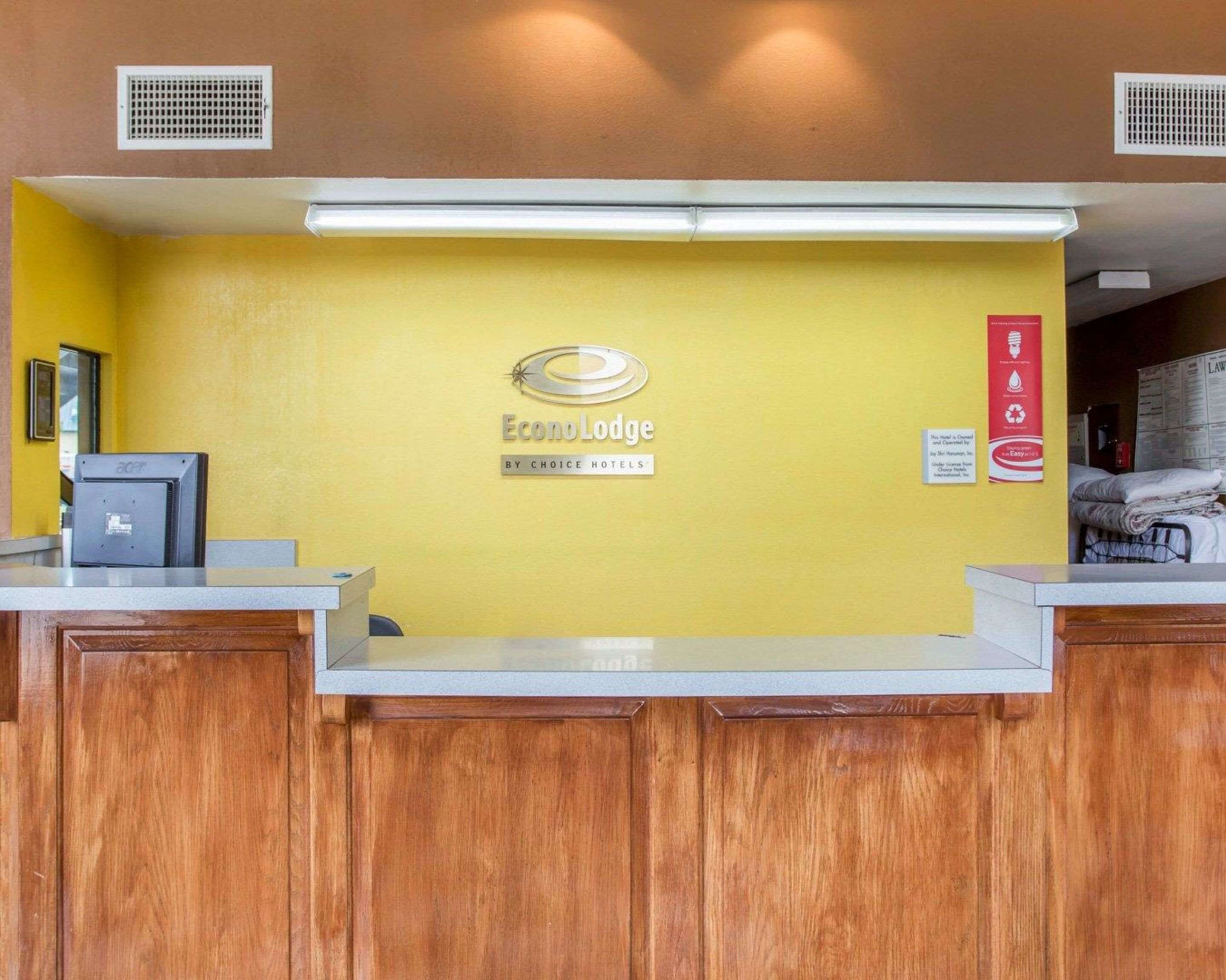 A reception desk at Econo Lodge with a yellow wall, a logo, and a sign indicating recycling.