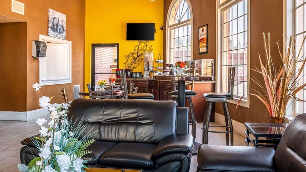 A spacious living area with a black leather sofa, a dining table with chairs, and a kitchen area in the background. - Econo Lodge Acworth East (Acworth)