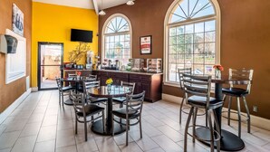 A dining area with a round table and chairs, a ceiling fan, and large windows. - Econo Lodge Acworth East (Acworth)