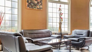 A spacious living room with a checkered floor, leather sofas, a glass coffee table, and large windows with a view. - Econo Lodge Acworth East (Acworth)