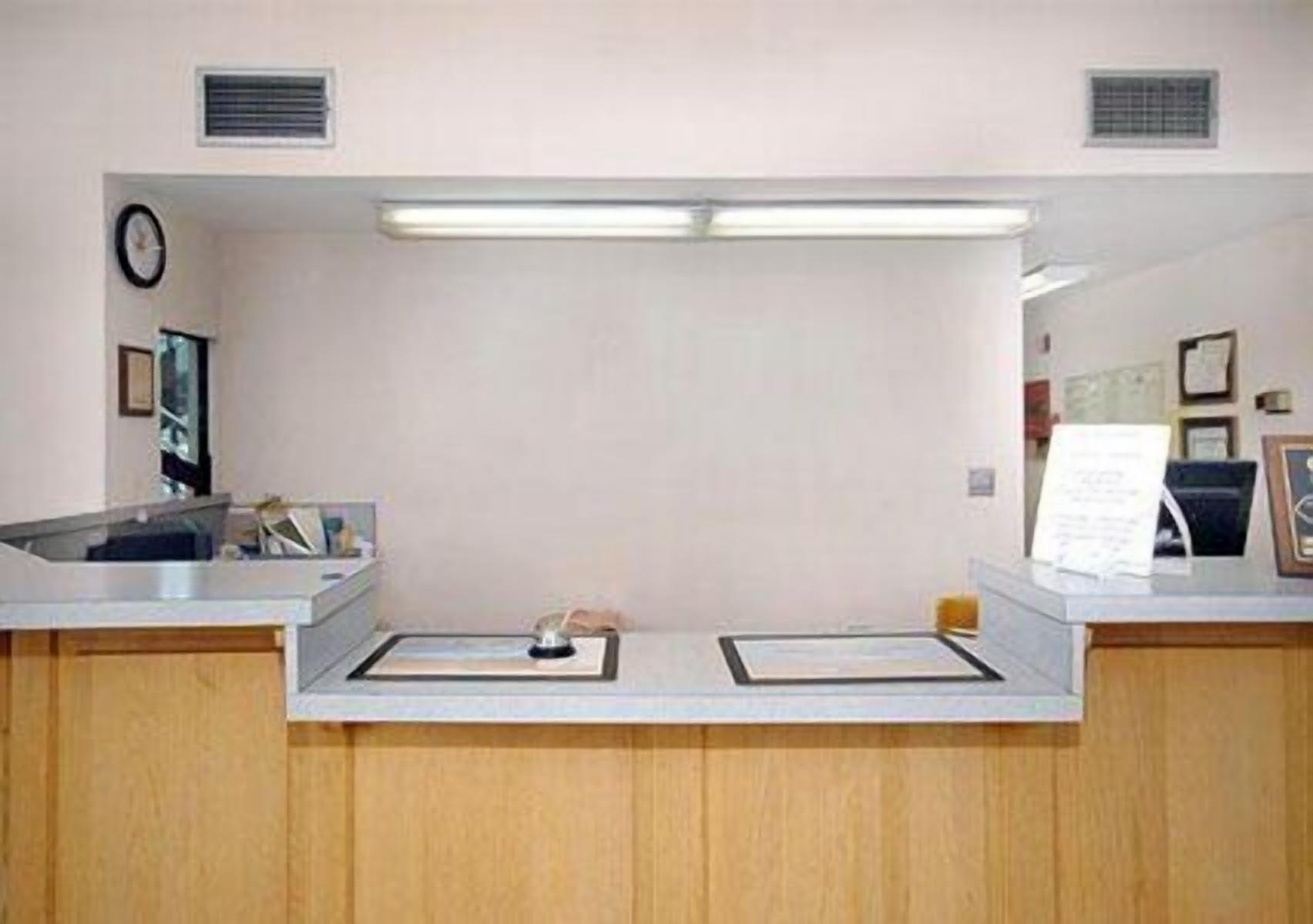 Una reception con un bancone in legno, una sveglia appesa al muro e un quadro incorniciato.