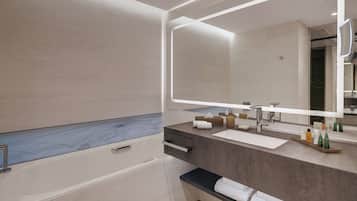 A modern bathroom with a bathtub, a large mirror, and a vanity with toiletries.