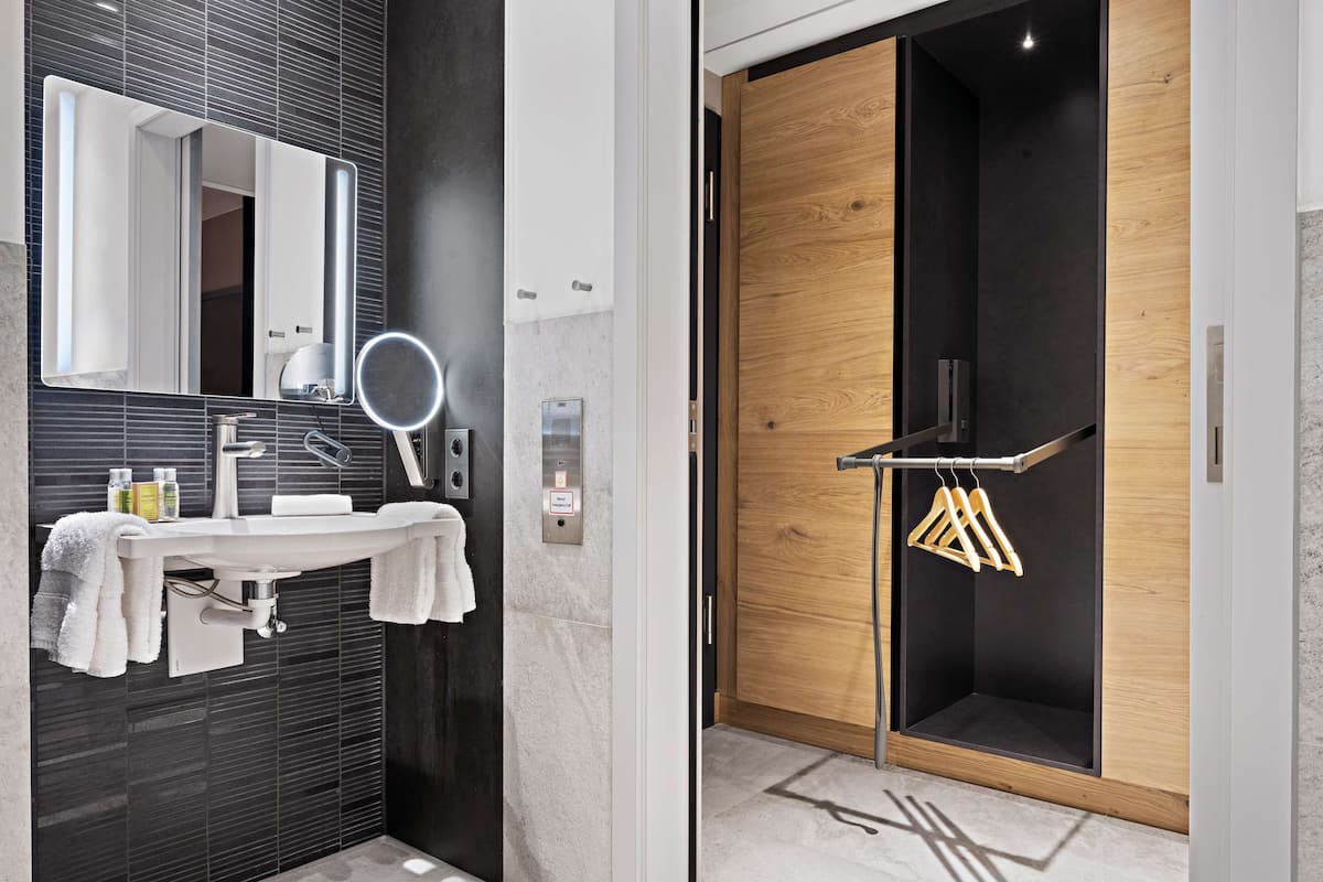A modern bathroom with a large mirror, sink, and towel rack.