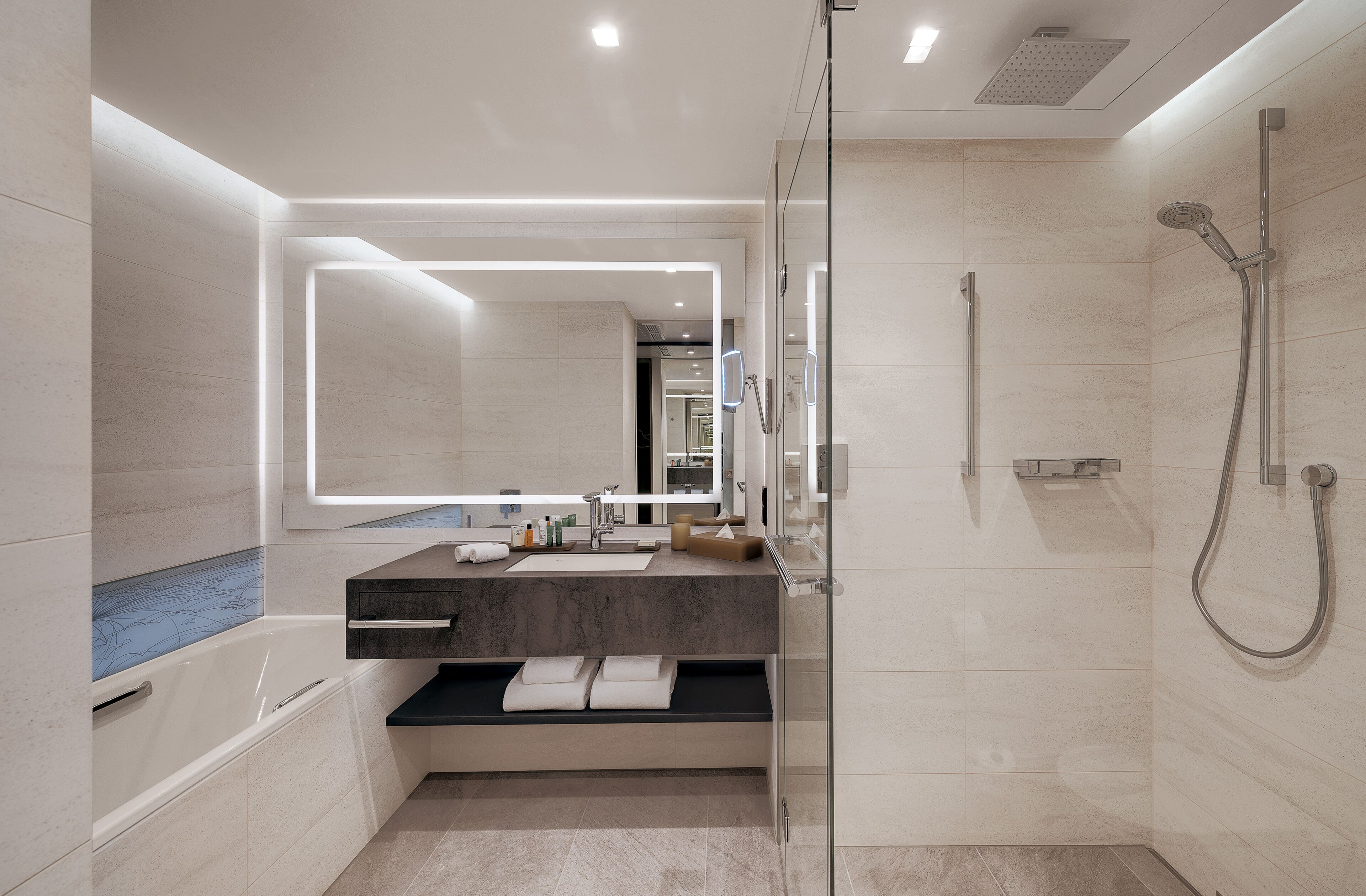 Une salle de bain moderne avec une douche à parois de verre, un grand miroir et une baignoire.