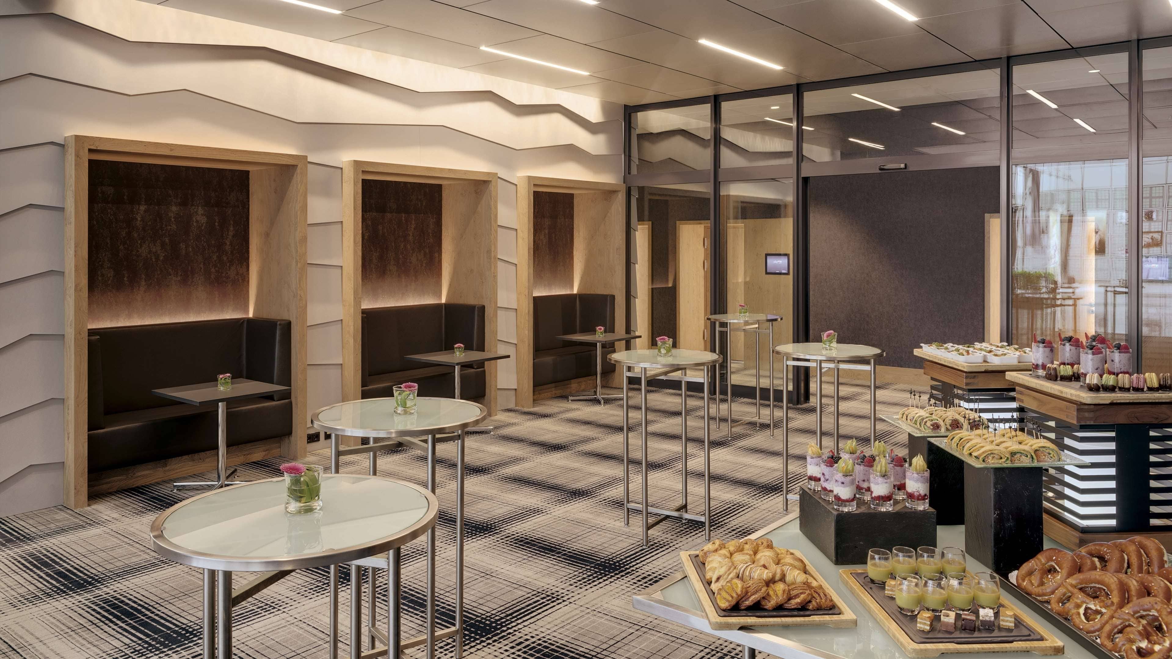A modern interior with seating areas, tables, and a food display.