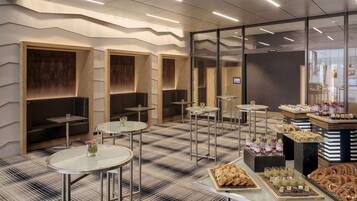 A modern interior with seating areas, tables, and a food display.