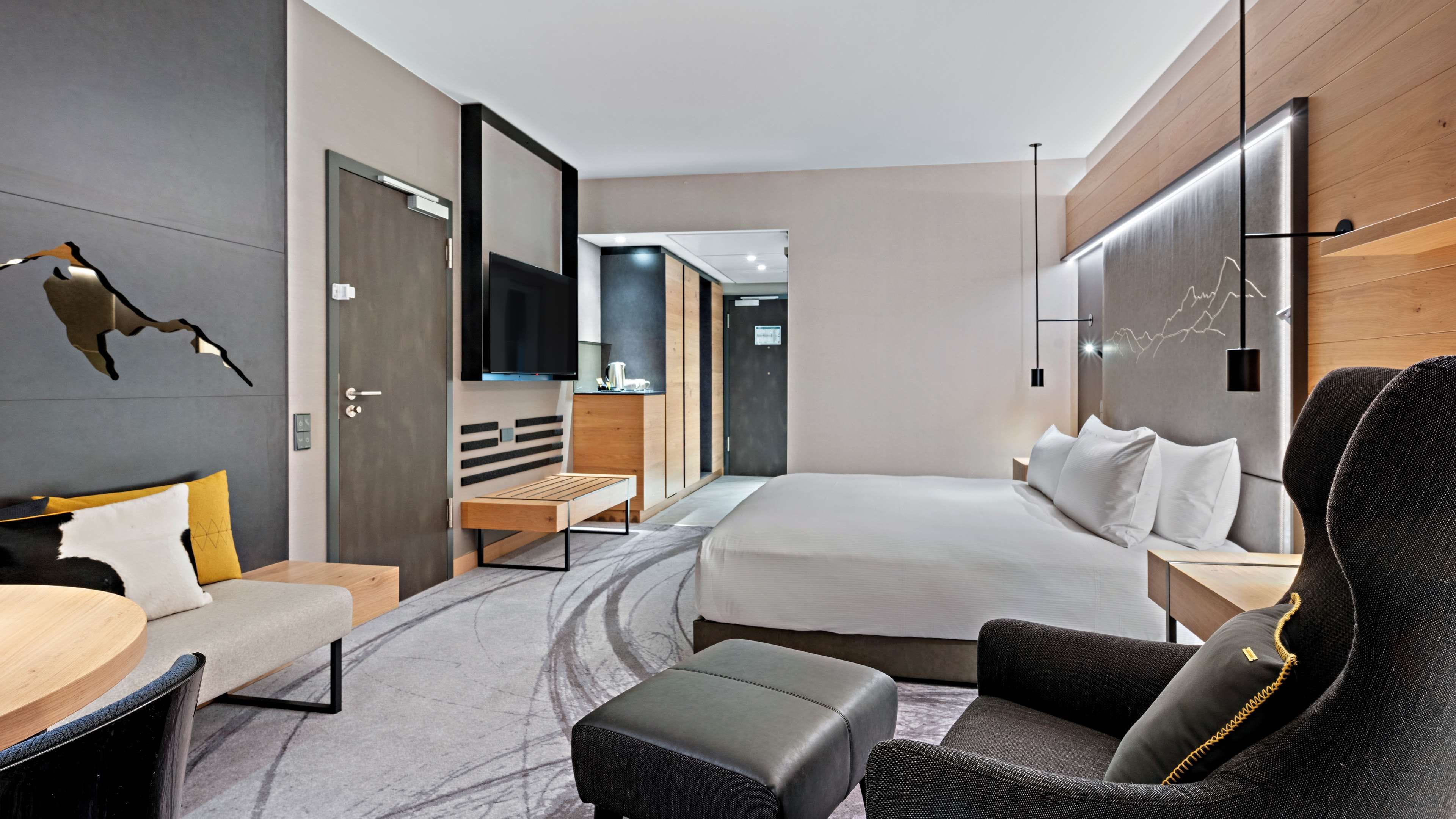 Una moderna camera d'albergo con un letto, una scrivania, una sedia e un divano.