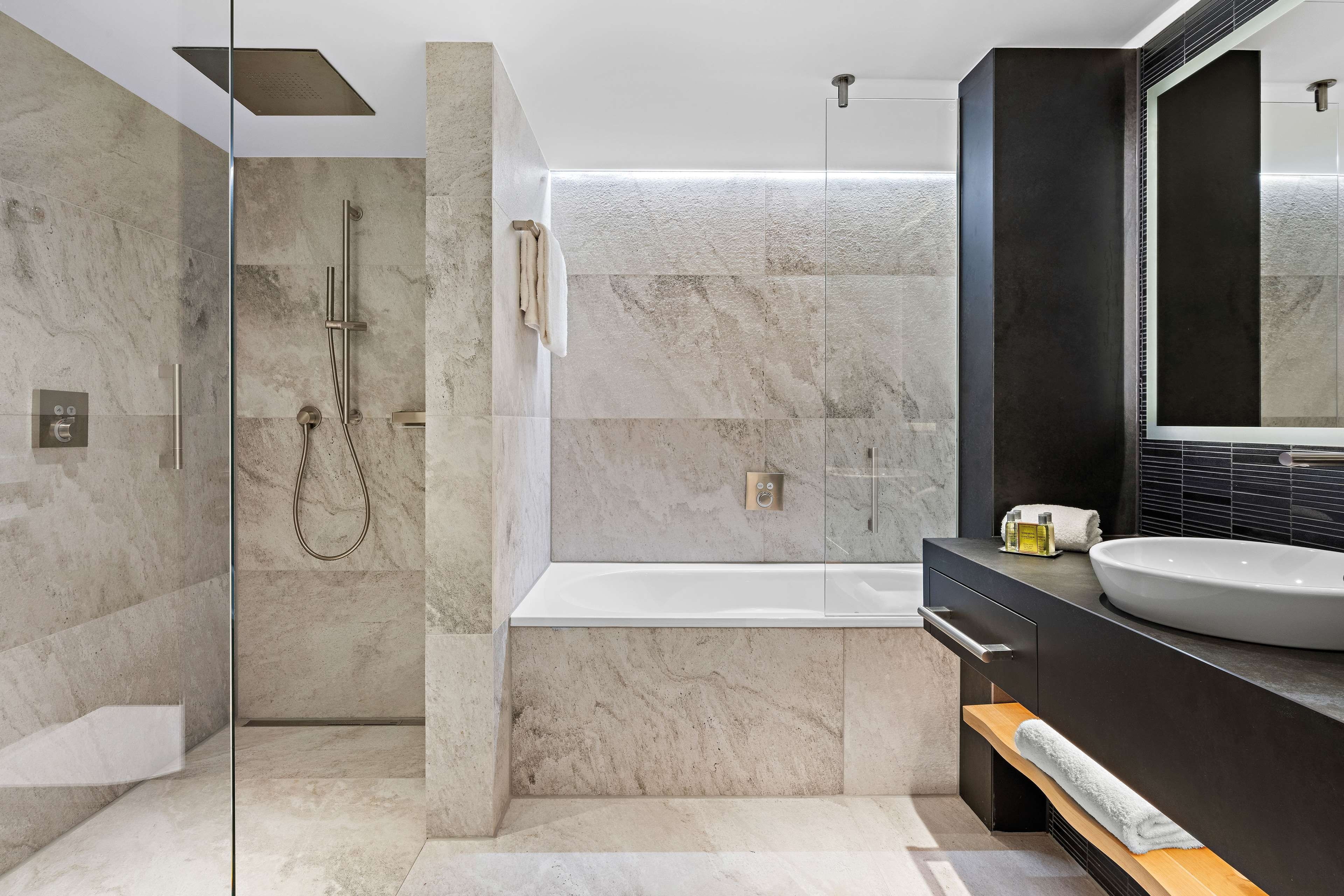 Une salle de bain moderne avec une douche à parois de verre, une baignoire sur pieds et un grand miroir.