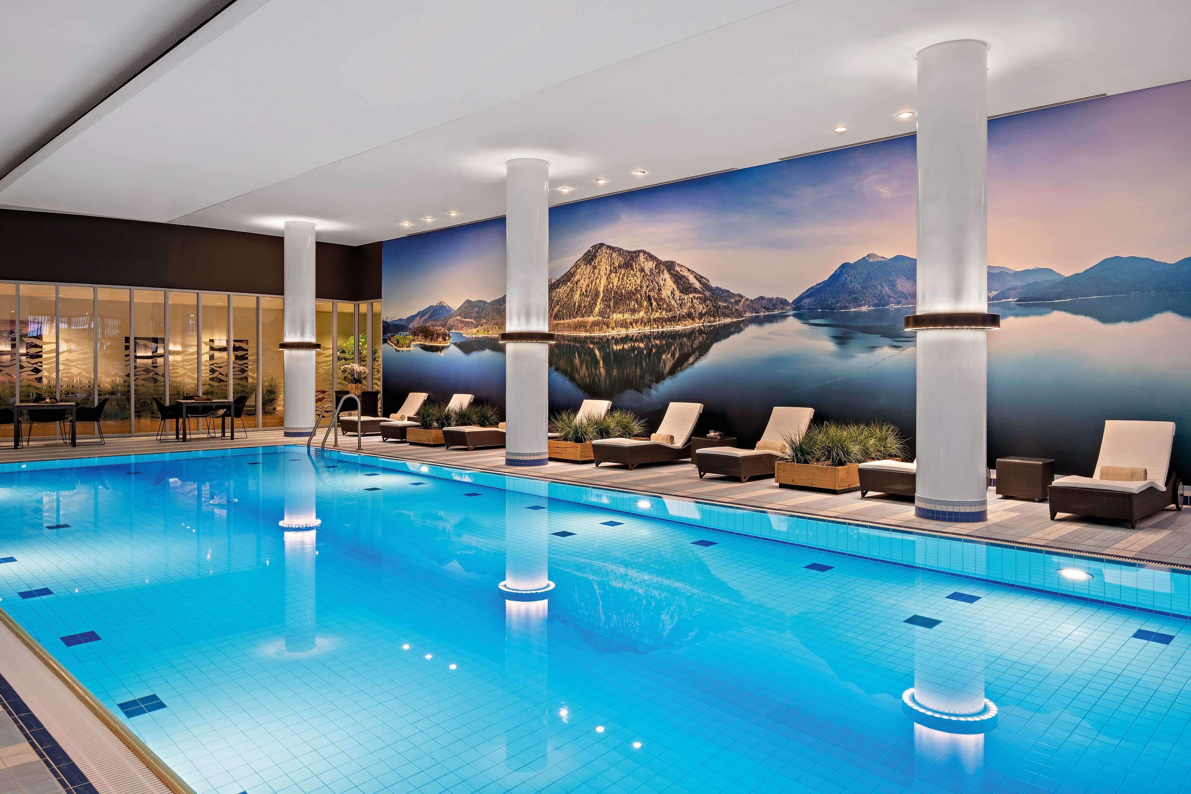 Una piscina con sillas de descanso y un mural de montañas y un lago.