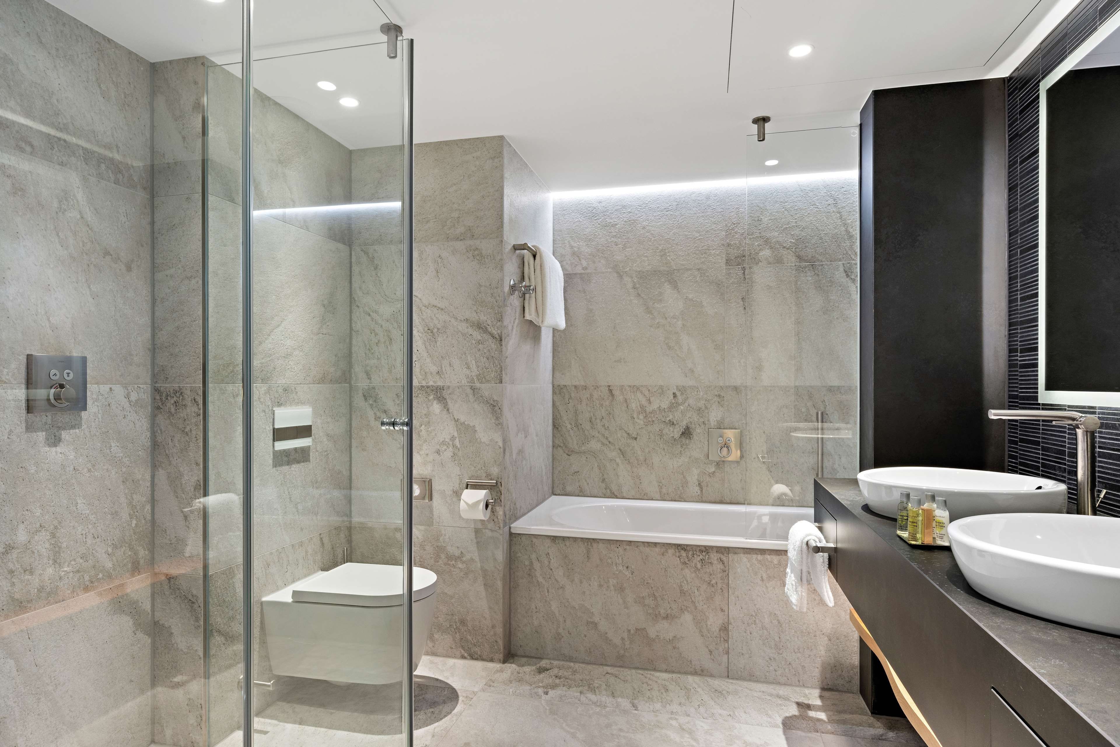 Un bagno moderno con doccia vetrata, una vasca da bagno indipendente e due lavandini.