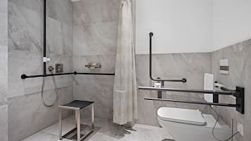 Un baño moderno con ducha, inodoro y barras de apoyo.
