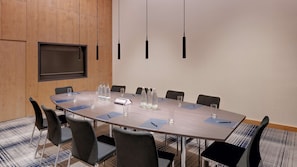 A conference room with a large table, chairs, a flat-screen TV, and water bottles.