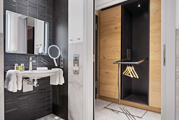 Un baño moderno con un espejo grande, un lavamanos y un perchero para toallas.