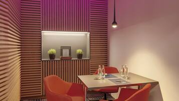 Una sala de reuniones moderna con una mesa, sillas y un techo inclinado con iluminación morada.