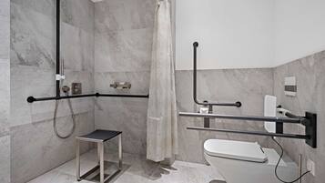 Ein modernes Badezimmer mit Dusche, Toilette und Haltegriffen.