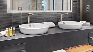 Un baño moderno con dos lavamanos, un espejo grande y un banco de madera.