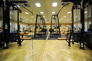 A gym with mirrored walls, exercise equipment, and a wooden floor.