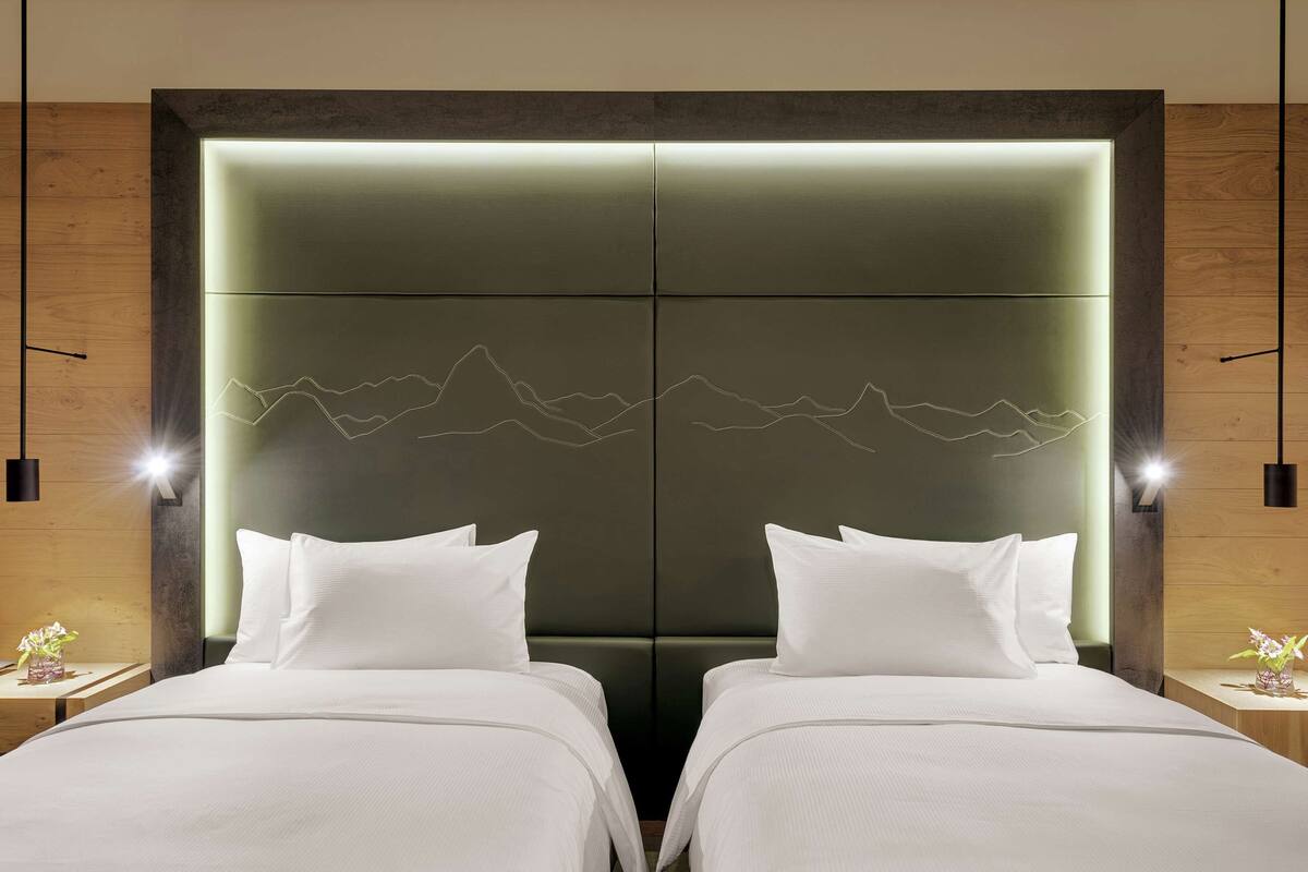 A hotel room with a large bed, two bedside tables, and a wall-mounted light fixture.
