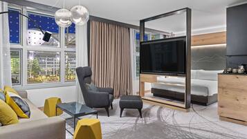 Ein stilvolles Wohnzimmer mit Sofa, Sessel, Hocker und einem Fernseher auf einem Holzboden.