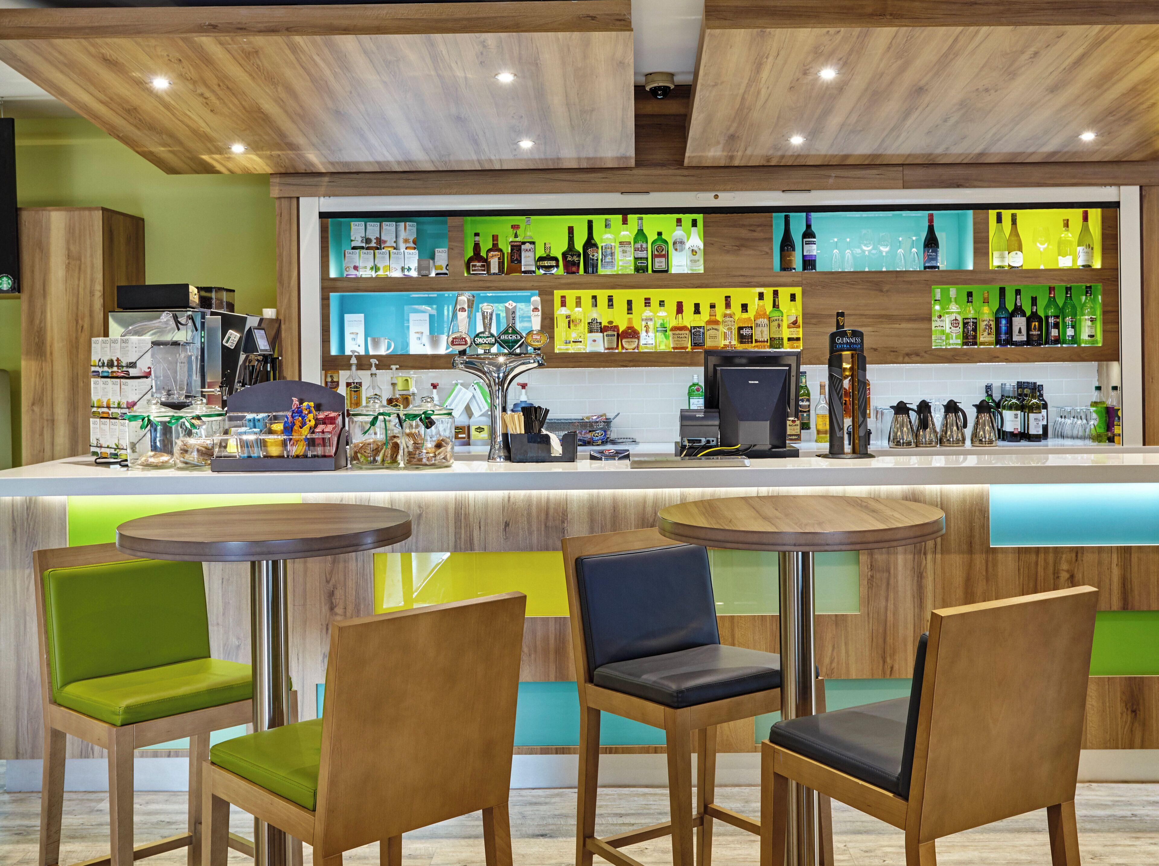 Eine Barbereich mit Holzkörpern, einer Kaffeemaschine und Regalen mit Flaschen.