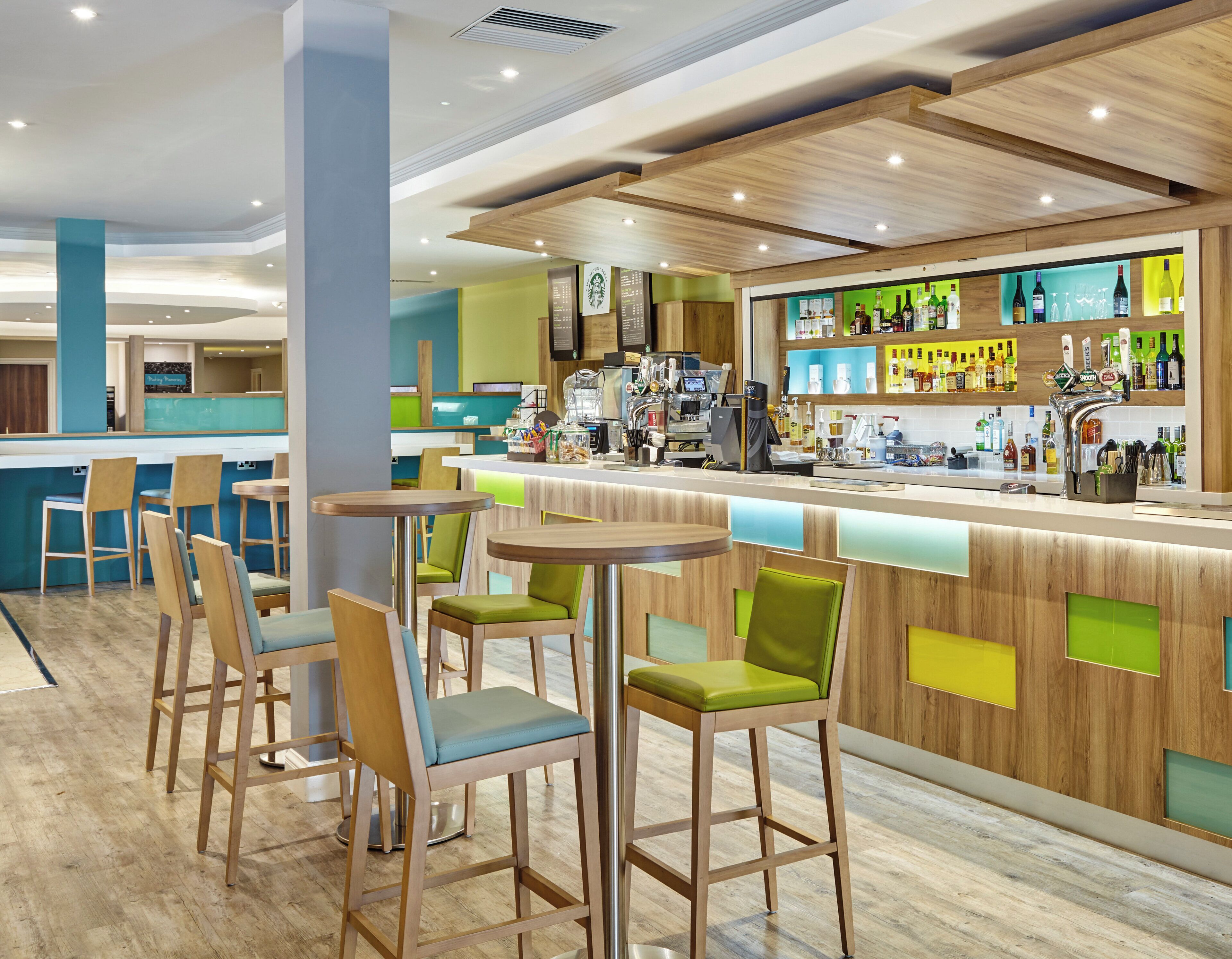 Zona de bar moderna con detalles de madera, asientos y una variedad de bebidas.