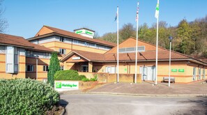 Un Holiday Inn con fachada de ladrillo, varias banderas y un césped bien cuidado.