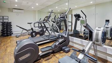 Un gimnasio con equipo de ejercicio diverso, incluyendo cintas de correr, elípticas y bancos de pesas.