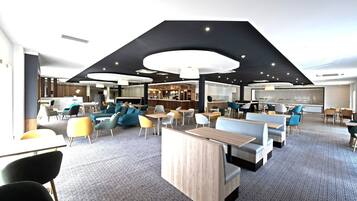 Een modern interieur met zithoeken, een bar en een keuken in de achtergrond.