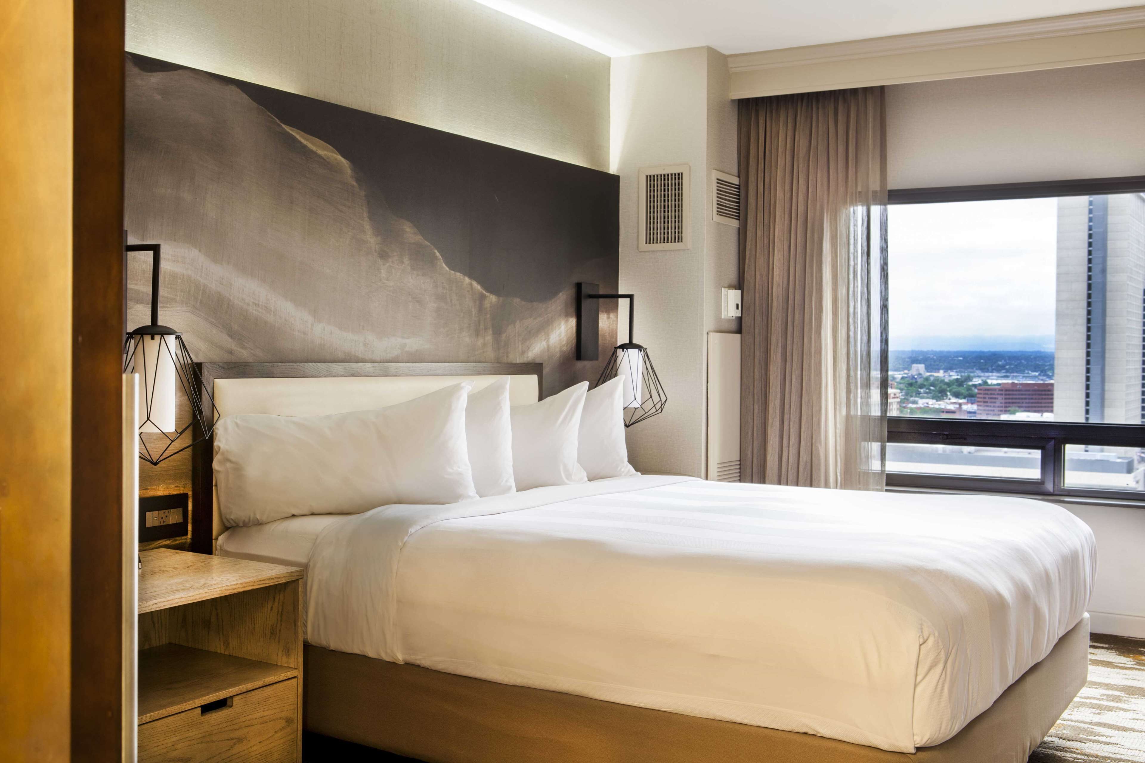 A hotel room with a large bed, a view of the city, and a modern design.