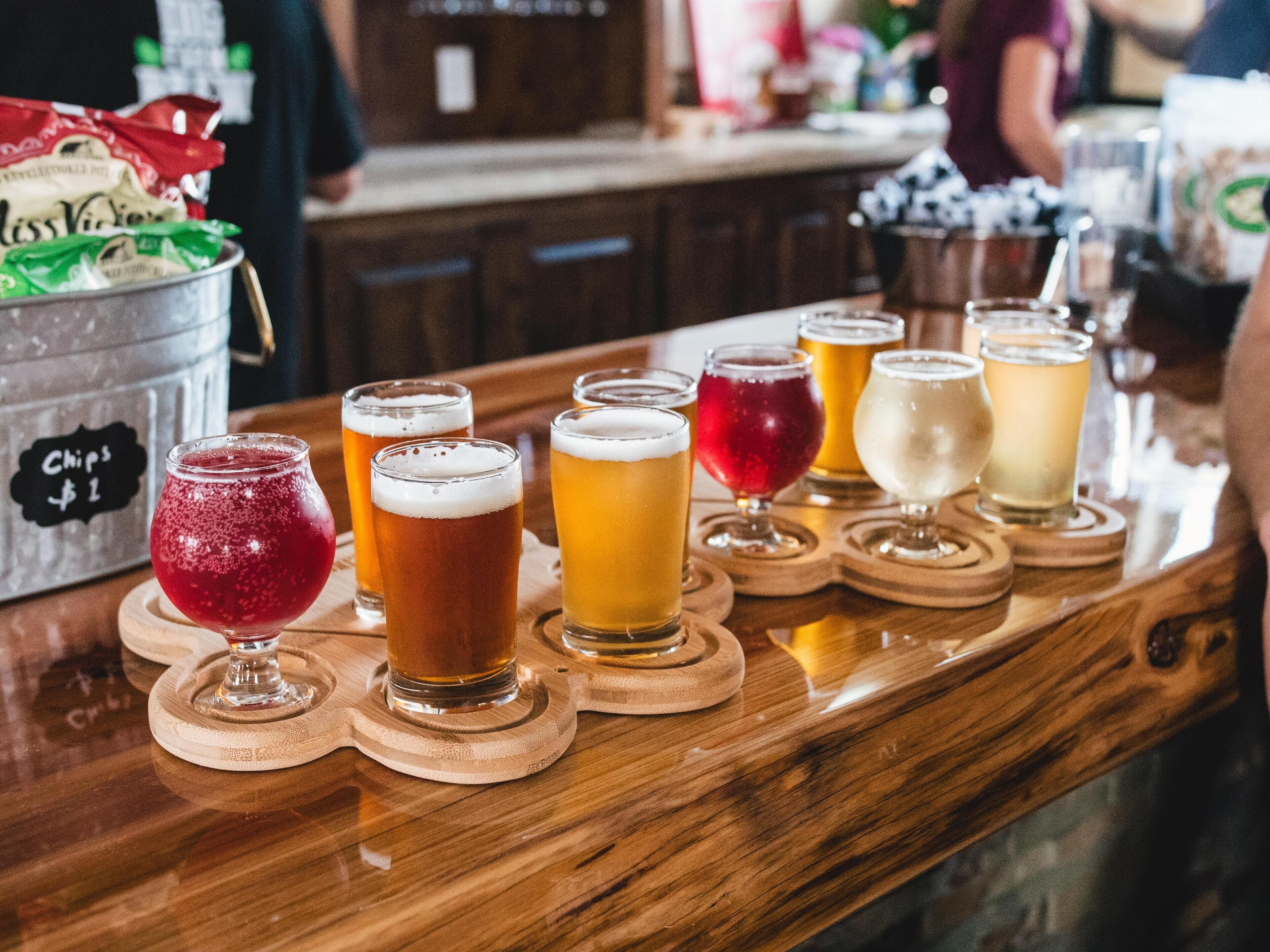 Balcão de bar com diversos copos de cerveja e um balde com a etiqueta 'Chips $1'.