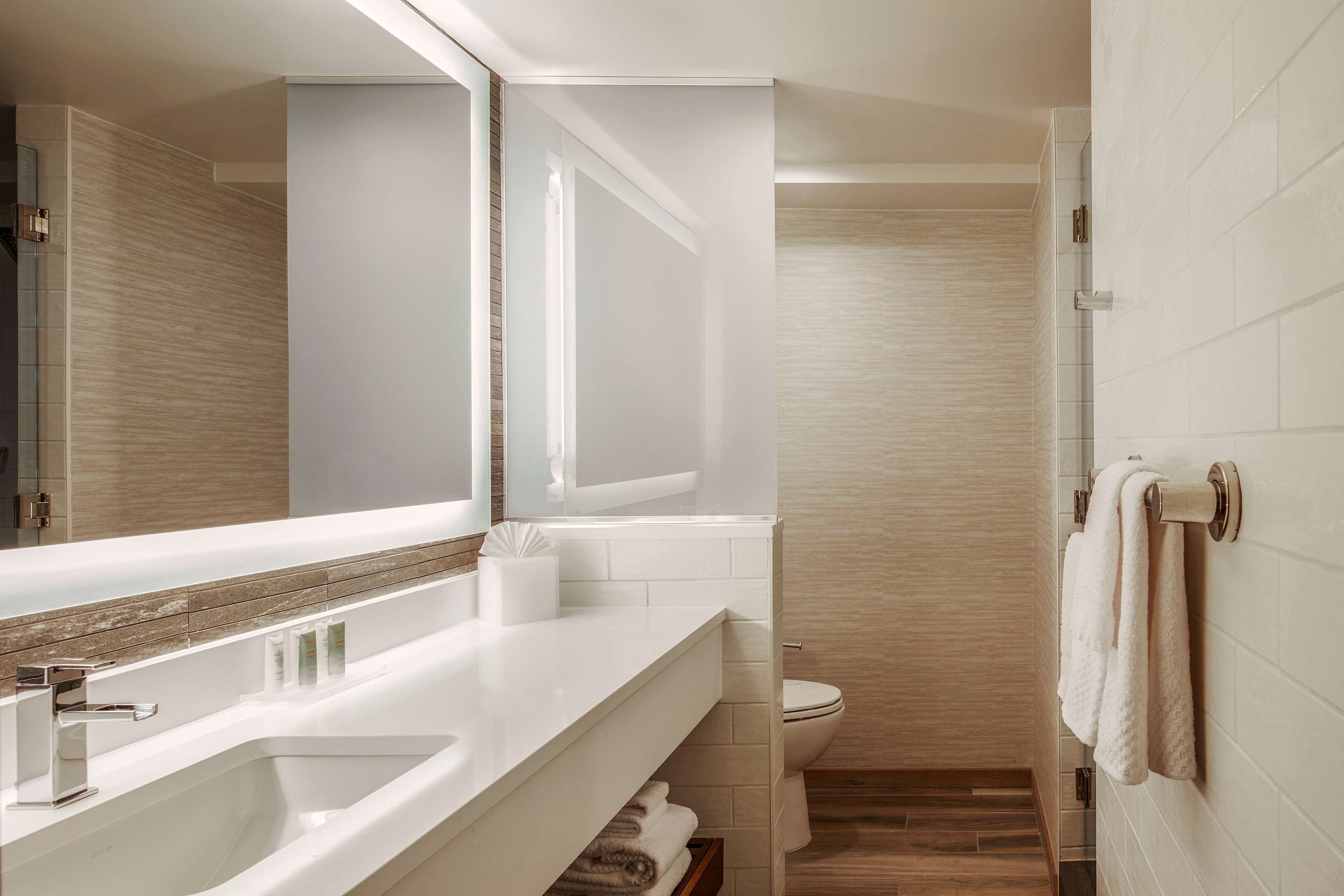 A modern bathroom with a large mirror, a bathtub, a toilet, and a shower area.