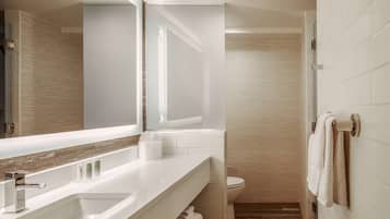 A modern bathroom with a large mirror, a bathtub, a toilet, and a shower area.