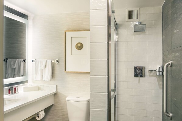 A modern bathroom with a glass shower enclosure, a white sink, and a toilet.