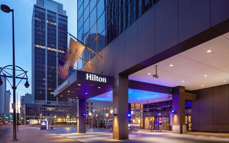 A Hilton hotel entrance with a glass facade, illuminated signage, and a modern architectural design.