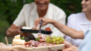 A wooden board with various cheeses, meats, and grapes.