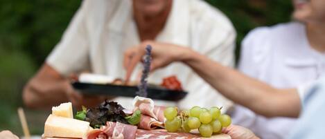 A wooden board with various cheeses, meats, and grapes.