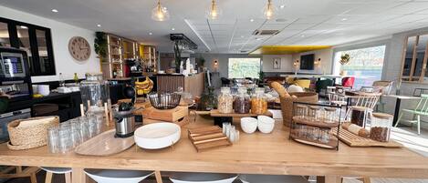 A restaurant interior with a wooden bar, seating area, and various food items displayed on the counter.