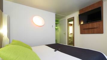 Une chambre d’hôtel avec un lit, un téléviseur à écran plat fixé au mur et un applique murale ronde.