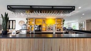 A modern bar area with a counter, shelves of bottles, and hanging glasses. - Campanile Chambray Les Tours (Chambray-les-Tours)