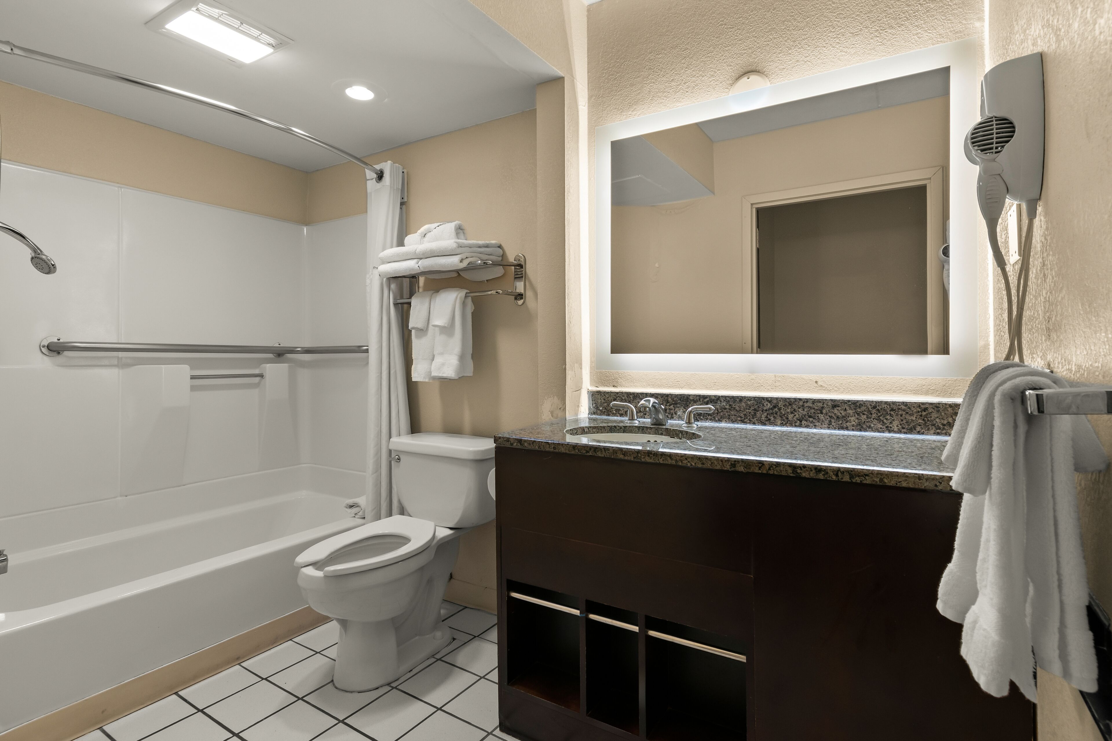 Ein Badezimmer mit Badewanne, Toilette und Waschtisch inklusive Spiegel und Handtuchhalter.