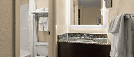 A bathroom with a toilet, shower, and sink.