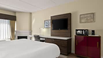 A hotel room with a bed, a desk, a television, a microwave, and a cabinet.