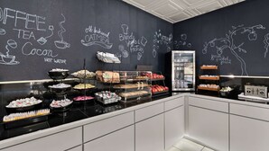 Ein Bereich mit Frühstücksbuffet und vielfältigen Speisen, an einer Tafel mit Zeichnungen zum Thema Essen.