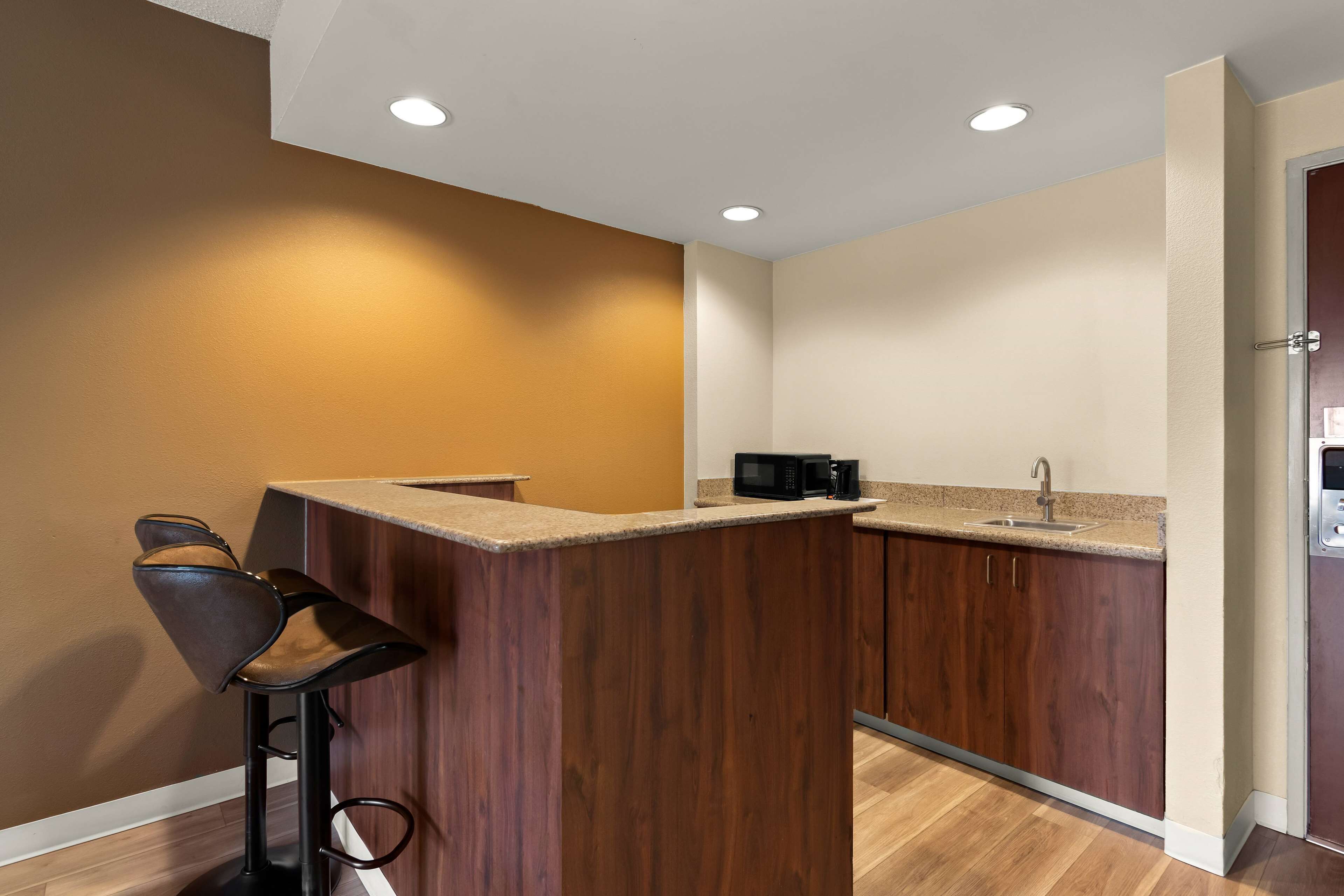 A kitchen with a wooden island, bar stools, a microwave, and a sink.