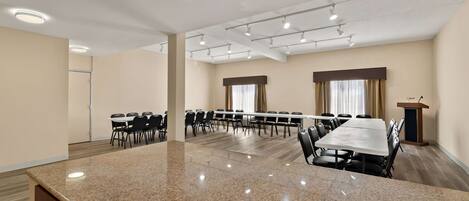 A conference room with a large granite table, multiple chairs, a podium, and a window with curtains.